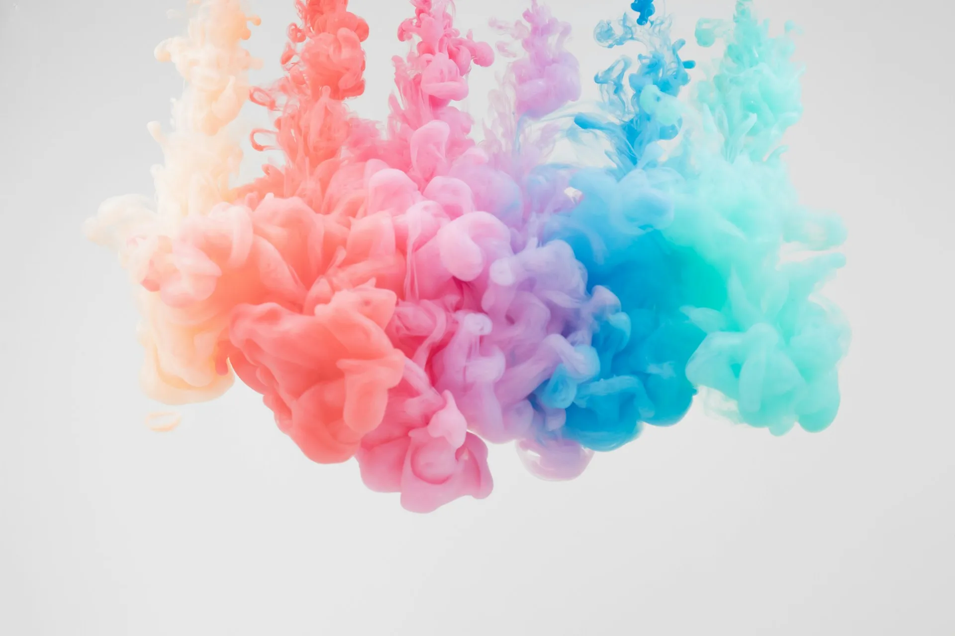 Colourful ink clouds in water Colourful ink clouds blending from pink to blue in water against a light background.