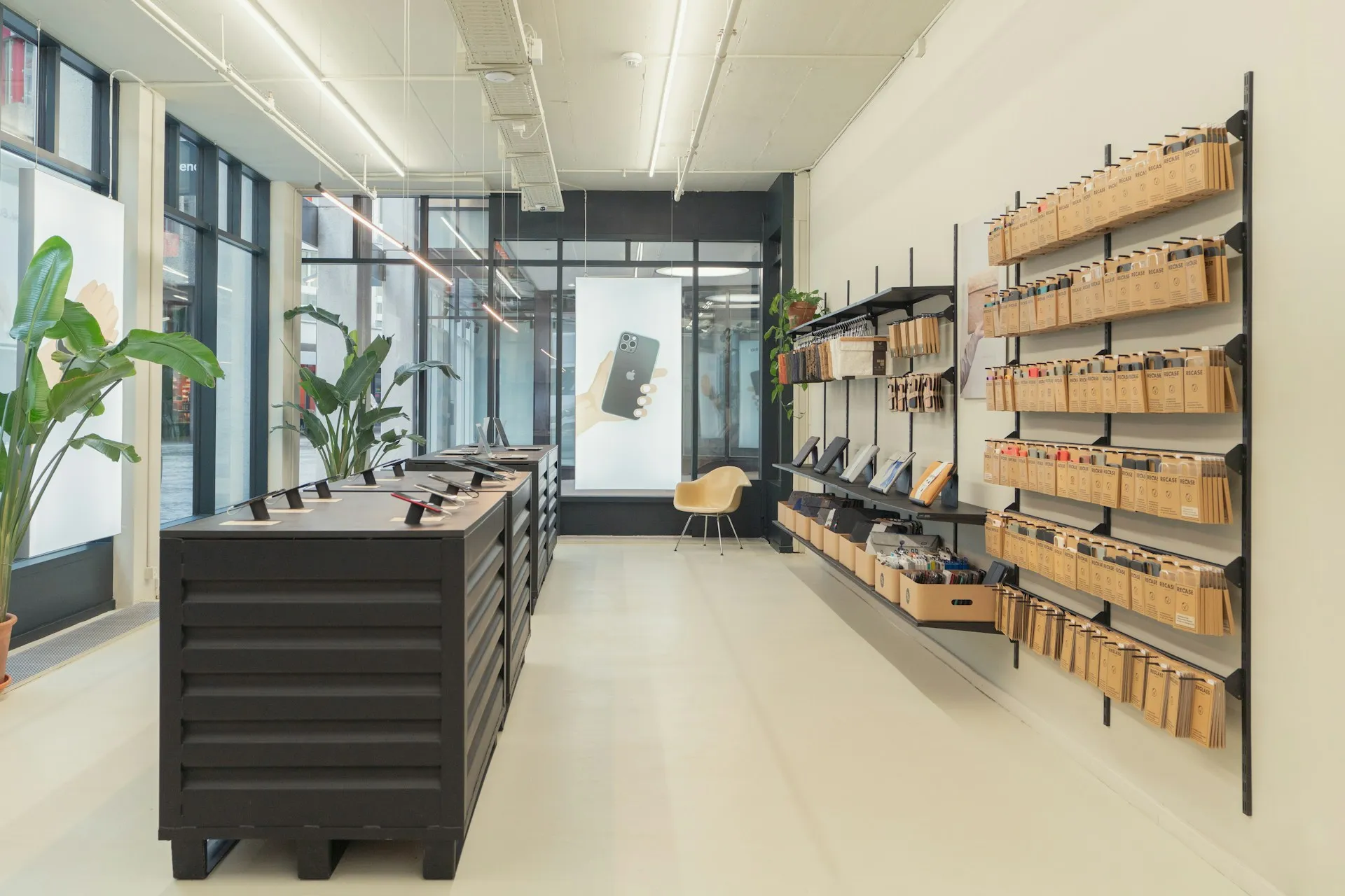 Modern retail store Modern retail store with minimalist interior, displaying tech accessories and phone cases on wall-mounted shelves, with tablets on central black counters.