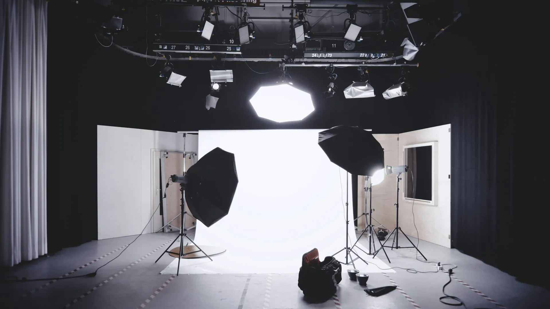 Professional photo studio setup Professional photo studio setup with large softbox lights, umbrellas, and a white backdrop surrounded by overhead lighting equipment.